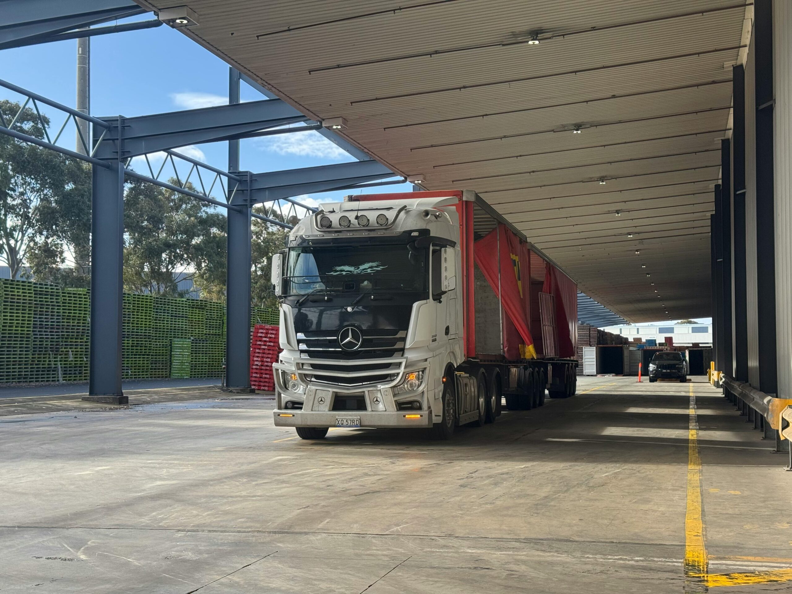 Large truck parked in a loading bay under a roof, ready for industrial transport.