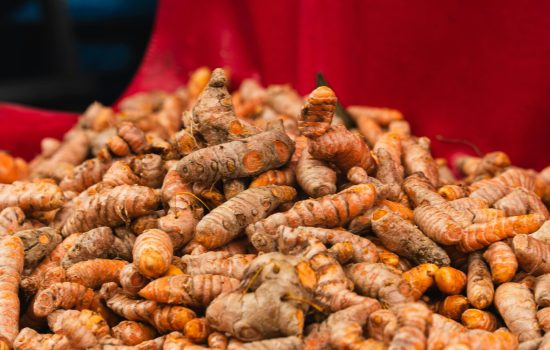 Freshly harvested turmeric roots displayed on red cloth at a local outdoor market.